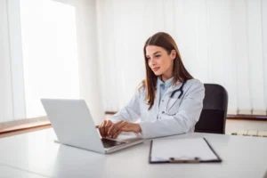 Foto de uma doutora sorrindo, utilizando o sistema de agendamento virtual da BurnUp pelo notebook da clínica de saúde onde trabalha.