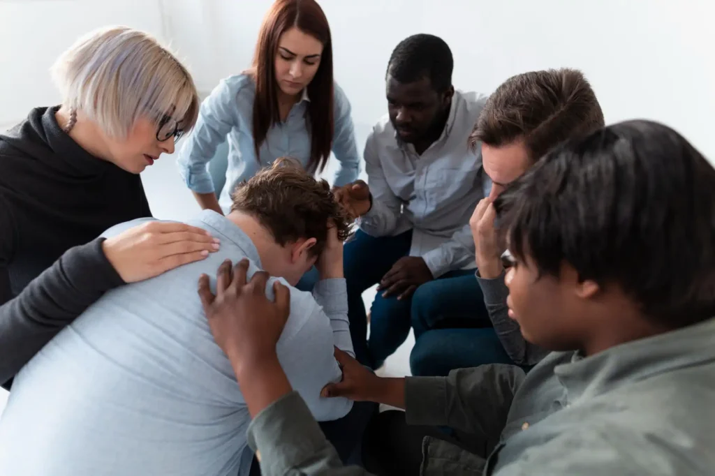 Foto de um grupo de pessoas prestando apoio a um colega de trabalho que sofre com as consequências da cultura do estigma no ambiente corporativo.