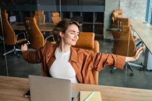 Foto de uma colaboradora em escritório moderno fazendo pausa para alongamento, representando equilíbrio vida-trabalho e bem-estar no ambiente corporativo.